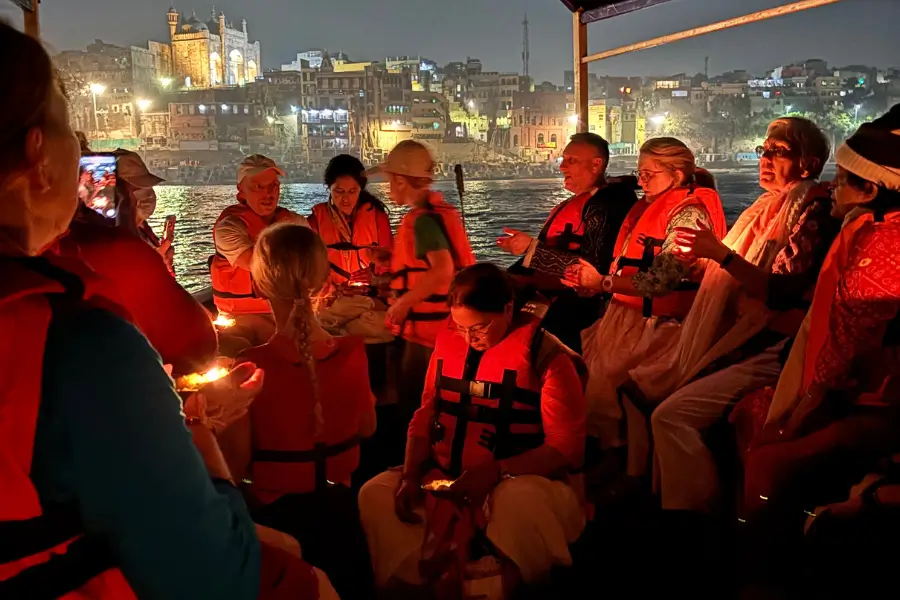 People holding candles during a nighttime gathering with city lights in the background.