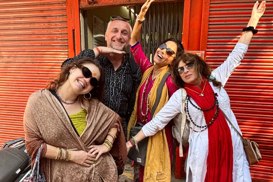 Four friends posing happily together outside a red wooden structure.